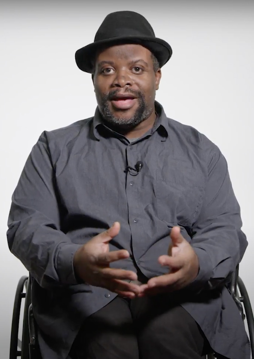 Photograph of David Hale, a Black man in a wheelchair. He’s facing the camera in the middle of speaking.