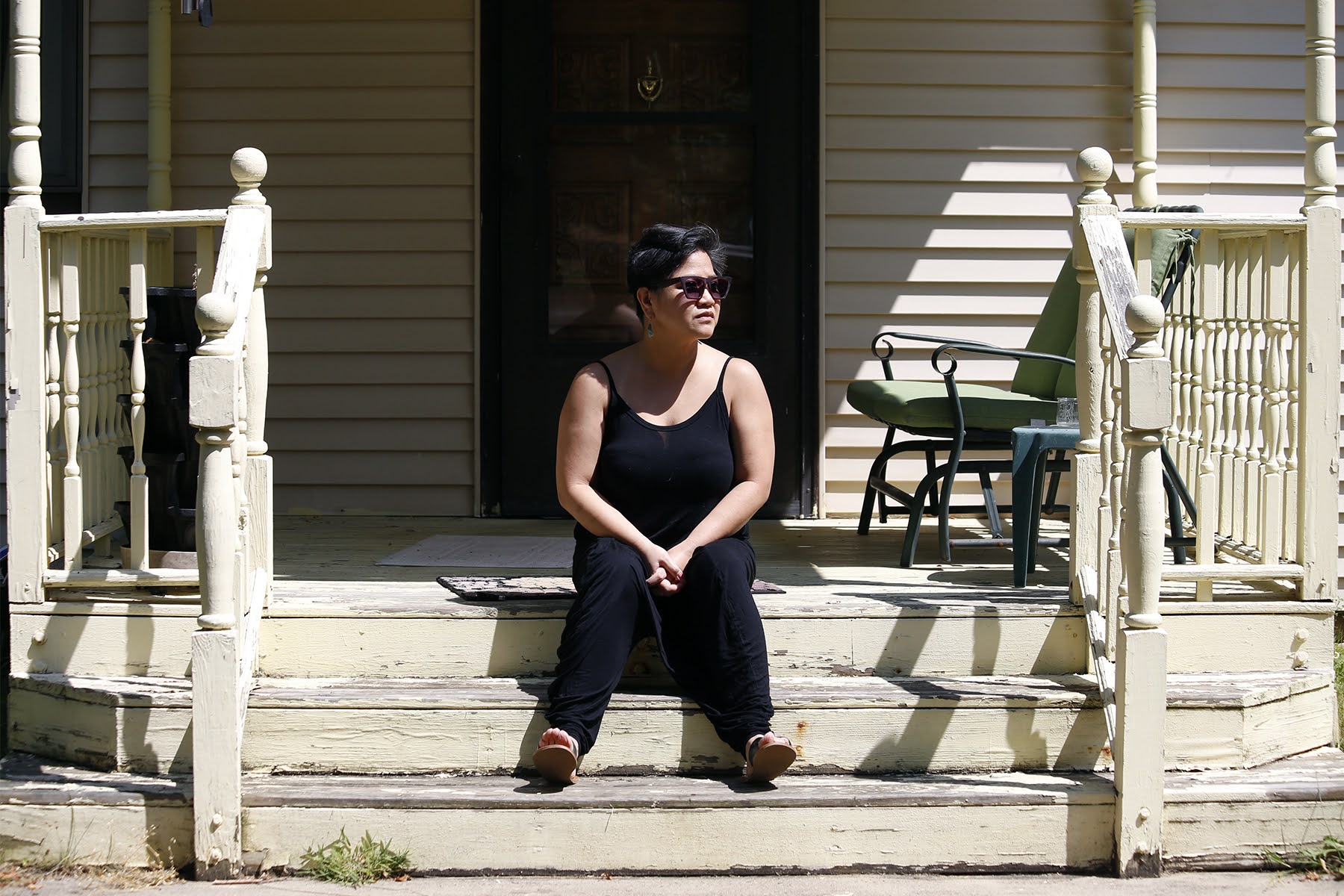 Photograph of Fran Flaherty sitting on the steps leading up to her home.