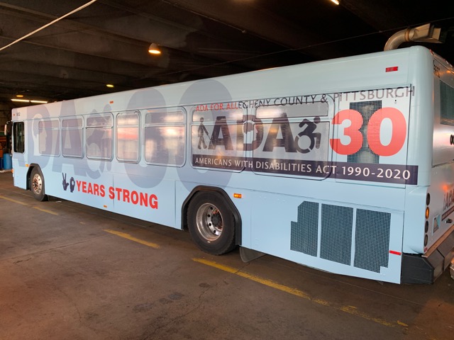 Photograph of a blue Port Authority bus in a garage. On its side is a decal that says 
