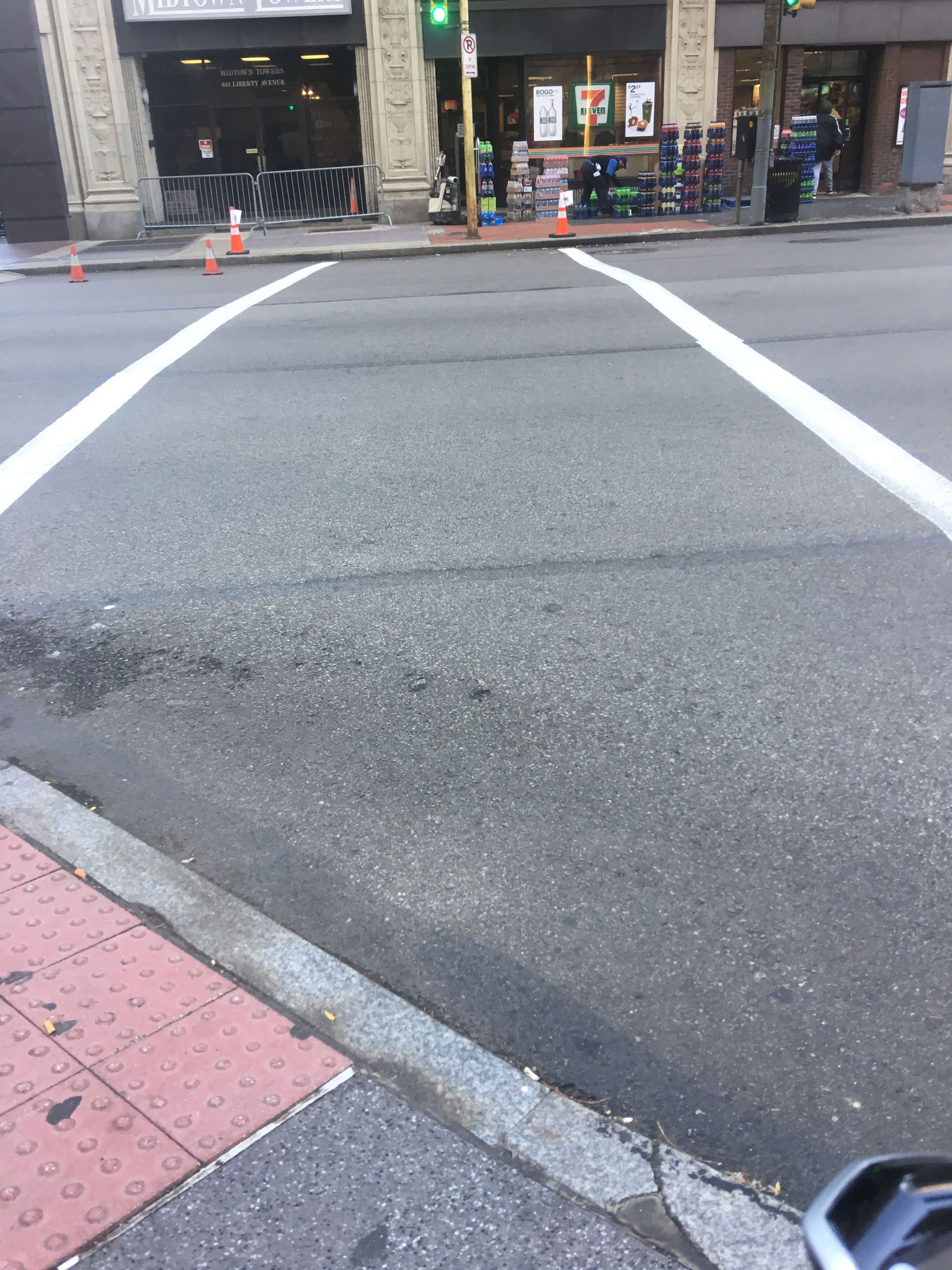 Photograph of a Downtown crosswalk. There’s a curb cut on one end of the crosswalk, but not the other.